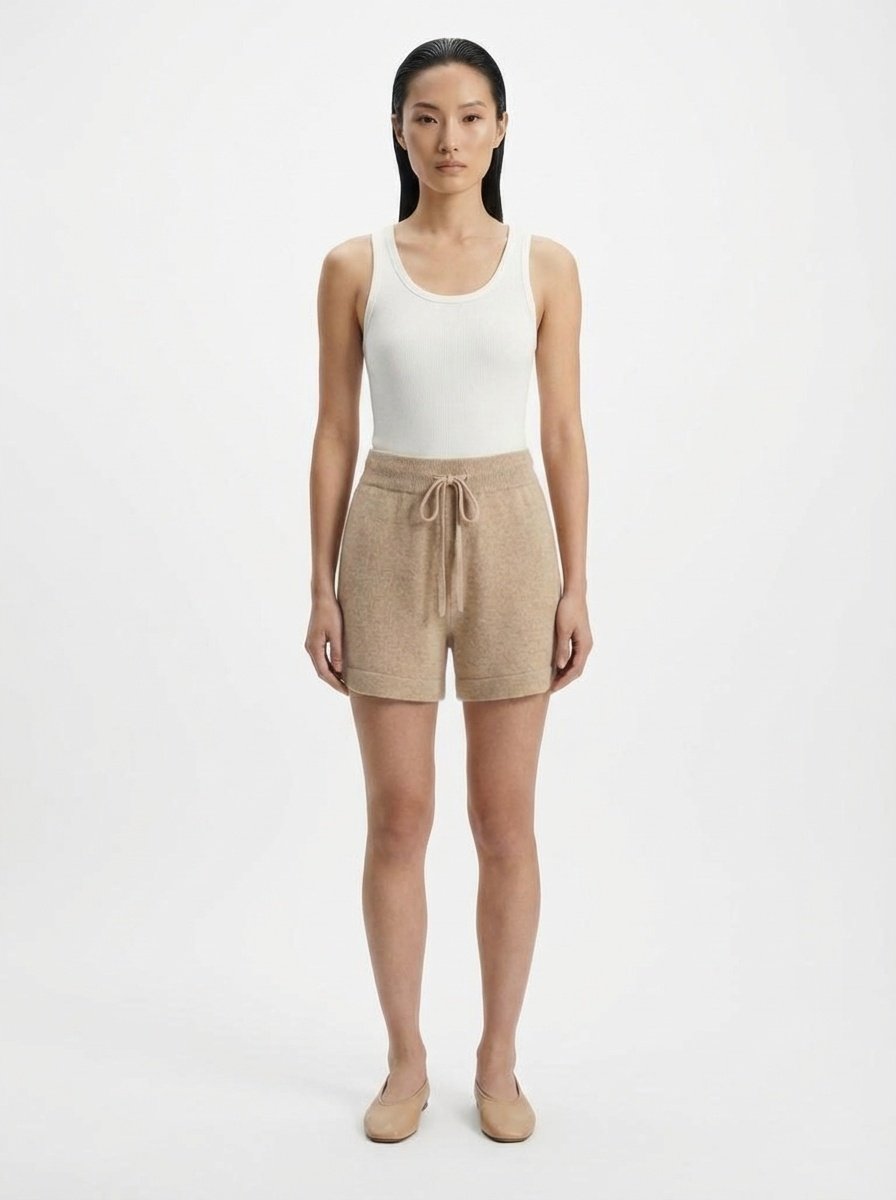 Woman wearing a white tank top and beige shorts on a white background